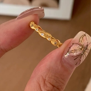 Close-up of textured gold ring with embedded small gemstones held by fingers