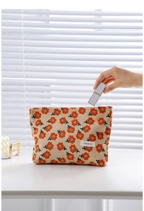 Detail of floral corduroy makeup bag showing storage capacity with a lipstick