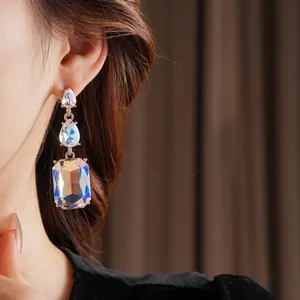 Elegant three-tier silver drop earrings featuring faceted crystals on a female model