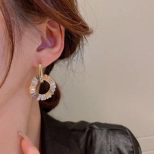 Close-up of gold hoop earring with clear and light purple crystals on model ear
