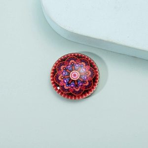 Macro shot of circular glass mandala fridge magnet with colorful geometric pattern