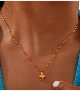 Close-up of gold-plated titanium necklace with tiny umbrella pendant on delicate bead chain