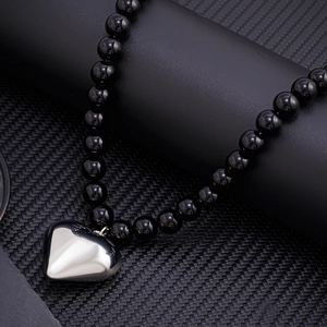 Men's hip hop beaded necklace with large silver heart pendant on a black textured surface