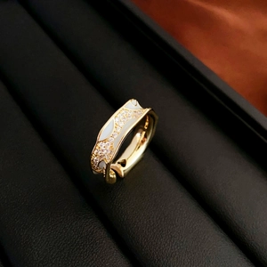 Macro view of gold heart ring with white enamel and sparkling zircon wave edges