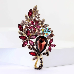 Macro shot of detailed golden alloy brooch with vibrant red crystals and floral rhinestones