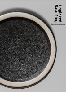 Macro detail of unglazed base ring on matte black ceramic teacup with grainy texture