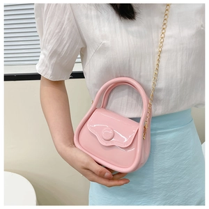 Detail of pink macaron mini jelly bag with gold chain strap on light clothing