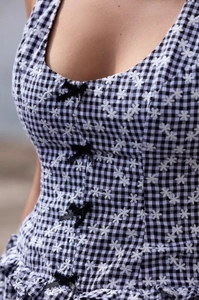 Close-up of black and white plaid dress with floral embroidery and black bow accents