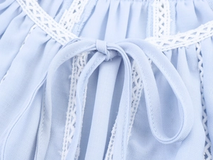 Detailed macro view of light blue shirt collar with white lace trim and bowtie tie-up