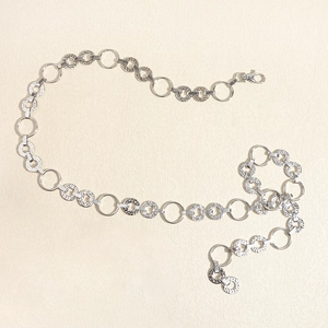 Dettaglio della cintura a catena in metallo argento con maglie rotonde lisce e lavorate