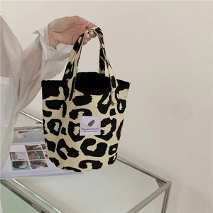 Detail of leopard print canvas tote bag with dual handles and text label design