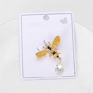 Detail of bee brooch with yellow enamel wings and teardrop crystal on display card