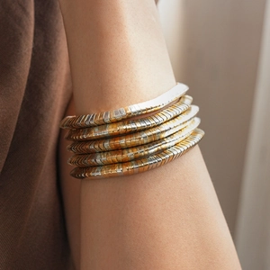 Detail of two-tone gold and silver multi-layer snake bone cuff worn on the upper arm
