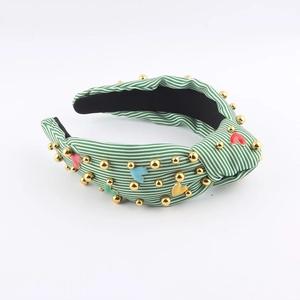 Detail of green and white striped knotted headband with colorful heart and gold beads