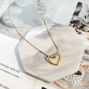 Détail d'un collier pendentif cœur évidé doré sur un sous-verre en marbre chic