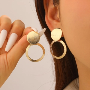 Detailed view of golden heart-shaped geometric earrings with brushed texture on ears