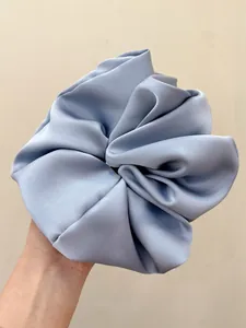 Macro detail of oversized light blue satin scrunchie with soft glossy fabric texture