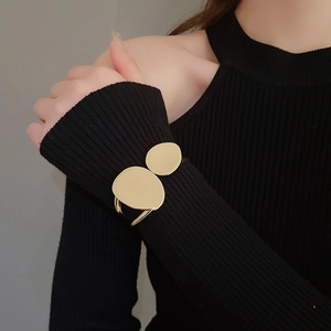 Close-up of a minimalist golden double disc open cuff bracelet on a model wrist