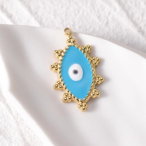 Detailed close-up of a 14k gold plated evil eye pendant with blue enamel on ceramic surface