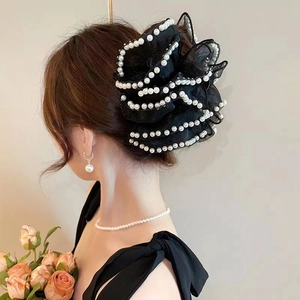 Detail of elegant black tulle hair claw with white pearl trim shown on hair back