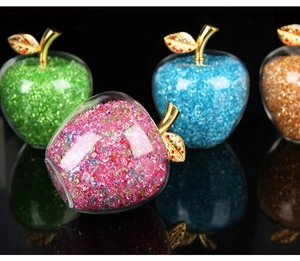 Close-up of glass crystal apples in pink, blue, green, and orange with golden stems