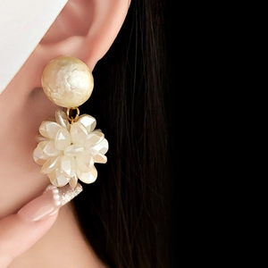 Detail of flower pearl drop earring worn by model with elegant floral design and lustrous pearls