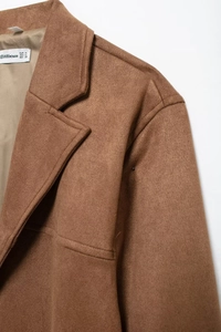 Close-up detail of the collar and shoulder of the brown faux suede blazer with brand label