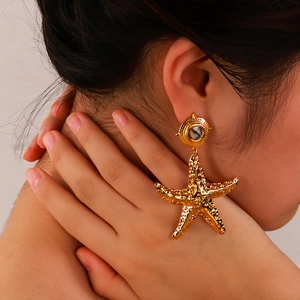 Bohemian gold starfish earrings with shell inlay on a female model, 18K gold plated jewelry