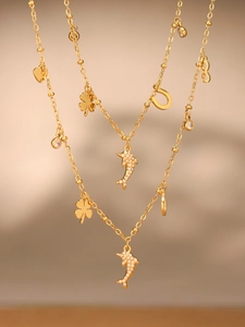 Detailed view of gold layered necklaces with dolphin, clover and horseshoe pendants
