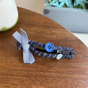Checkered blue hair scrunchie with bow and button detail on a wooden surface