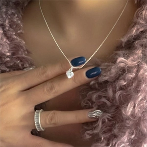 Detail of silver heart pendant necklace with shimmering zircon stones on a model