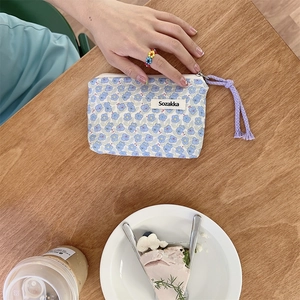 Dettaglio della pochette floreale con cordino viola su un tavolo da tè in legno