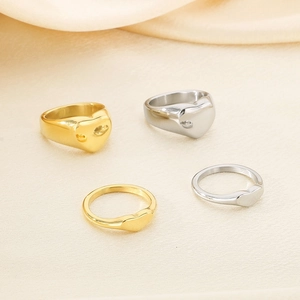 Flat lay of gold and silver heart-shaped stainless steel rings on soft beige fabric