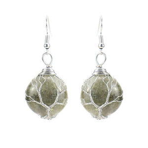 Detailed view of handmade silver wire-wrapped tree of life earrings with natural green stone