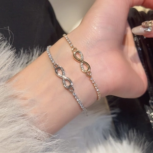 Detail of elegant gold and silver infinity bracelets with zircon stones on wrist