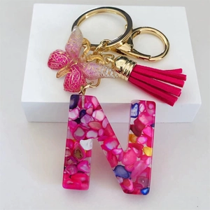 Detail of resin letter N keychain with pink glitter butterfly and soft silk tassel