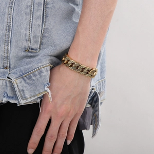 Détail d'un bracelet gourmette gravé de style rétro doré porté par un homme