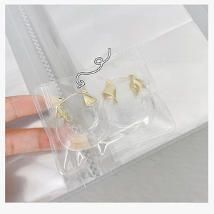 Macro view of twisted gold earrings in a transparent anti-oxidation PVC storage bag