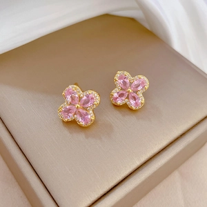Detail of four-leaf flower gold earrings with pink teardrop zirconia in a gift box