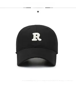 Close-up of black baseball cap featuring white embroidered R letter on a curved brim hat
