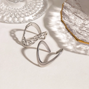 Close-up of minimalist silver adjustable rings with chain and wave patterns in sunlight