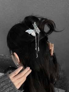 Detail view of butterfly hair claw with pearls and long tassels on black hair