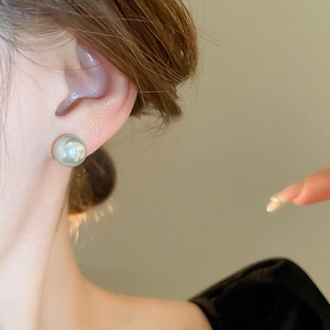 Close-up of a minimalist silver-grey round pearl earring worn on the earlobe