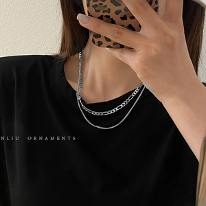 Detail of silver double-layer layered necklace featuring Figaro chain and curb chain links