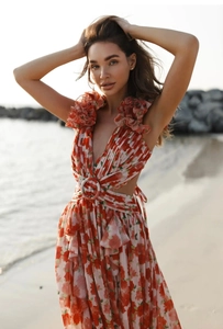 Detail of red floral maxi dress with deep V-neckline, waist cutout, and ruffle shoulders