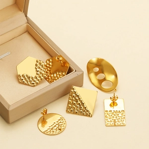 Detailed macro view of geometric gold earrings with hammer texture on warm background
