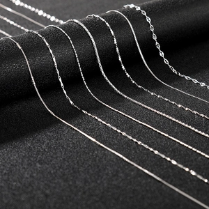 Macro shot of assorted silver chain necklaces including box and snake links on black fabric