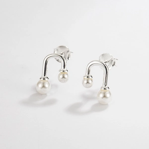 Macro shot of 925 silver U-shaped earrings with asymmetrical double white pearls