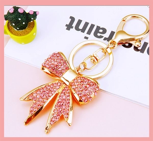 Detail of pink crystal bow keychain with golden alloy finish and metallic keyring