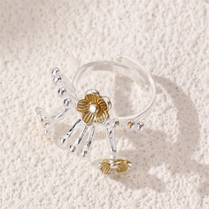 Detail of silver ring with gold plum blossoms and pearl tassels on a stone surface